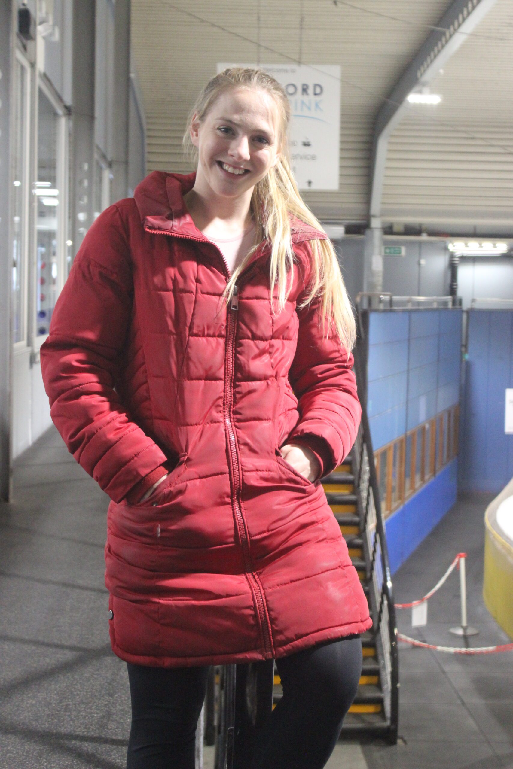 Oxford Ice Skating Coach Lydia Smart standing at the top of the Oxford ice rink stairs. She's ready to be your ice skating coach with a smile on her face.